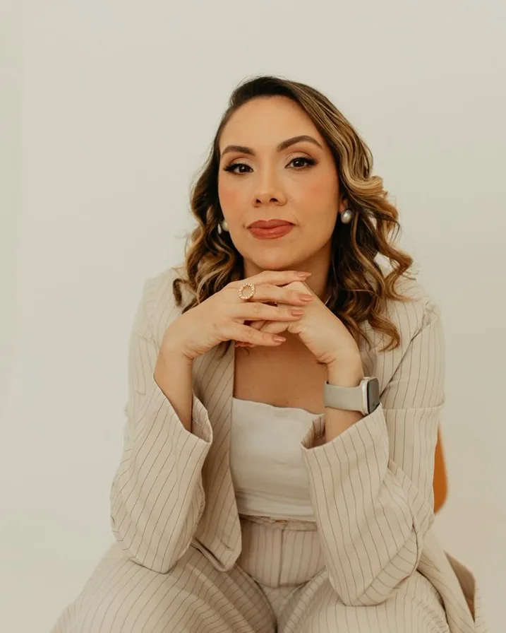 Brenna Damasceno, fundadora e supervisora da clínica, sorrindo com as mãos sob o queixo